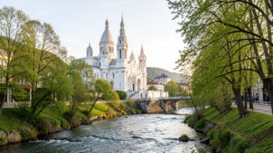 Vue matinale réaliste du Sanctuaire Notre-Dame de Lourdes, avec ses basiliques blanches, le gave de Pau et une douce lumière printanière.